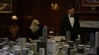Movie still from “Oats Studios” (2017), directed by Neill Blomkamp – Two men in a room with a model of a city; Medium shot, Over the shoulder angle