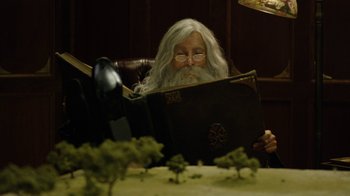 Movie still from “Oats Studios” (2017), directed by Neill Blomkamp – An old man with long white hair reading a book; Medium shot, Low angle