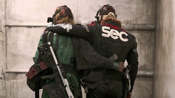 Movie still from “Oats Studios” (2017), directed by Neill Blomkamp – A couple of people that are standing next to each other; Medium shot, Over the shoulder angle