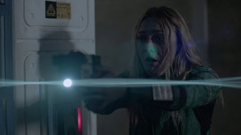 Movie still from “Oats Studios” (2017), directed by Neill Blomkamp – A woman is holding a gun in her hand; Close Up shot, Over the shoulder angle