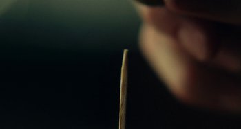 Movie still from “Obsession” (2023), directed by Glenn Leyburn – A person holding a wooden stick in their hand; Extreme Close Up shot, High angle