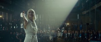 Movie still from “Okja” (2017), directed by Bong Joon Ho – A woman standing at a podium in front of an audience; Medium shot, Over the shoulder angle