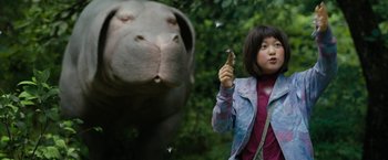 Movie still from “Okja” (2017), directed by Bong Joon Ho – A woman standing next to an animal in a forest; Medium shot, Low angle