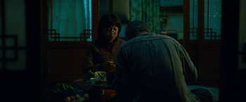 Movie still from “Okja” (2017), directed by Bong Joon Ho – A woman sitting at a table with a plate of food in front of a man; Medium shot, Over the shoulder angle