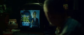 Movie still from “Okja” (2017), directed by Bong Joon Ho – A man is watching a television with a picture of a man on it; Extreme Close Up shot, Over the shoulder angle