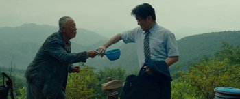 Movie still from “Okja” (2017), directed by Bong Joon Ho – A man handing a bowl to another man holding a blue bowl; Medium shot, Low angle