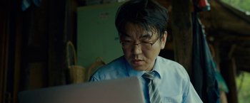 Movie still from “Okja” (2017), directed by Bong Joon Ho – A man wearing a tie looking at a computer screen; Close Up shot, Low angle