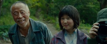 Movie still from “Okja” (2017), directed by Bong Joon Ho – A young girl standing next to a man in the woods; Close Up shot, Low angle