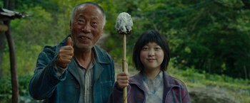 Movie still from “Okja” (2017), directed by Bong Joon Ho – An older man and a young girl holding a stick; Medium shot, Low angle