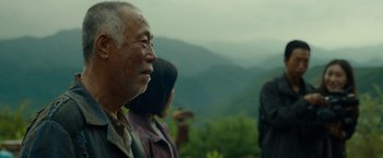 Movie still from “Okja” (2017), directed by Bong Joon Ho – An older man standing in front of a group of people on top of a hill; Medium shot, Low angle