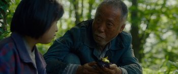 Movie still from “Okja” (2017), directed by Bong Joon Ho – An older man and a young woman looking at a flower; Close Up shot, Over the shoulder angle