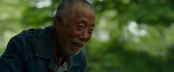 Movie still from “Okja” (2017), directed by Bong Joon Ho – An older man is smiling and looking at the camera; Close Up shot, Over the shoulder angle
