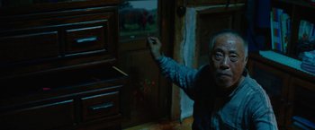 Movie still from “Okja” (2017), directed by Bong Joon Ho – An older man pointing to a painting on the wall; Medium shot, High angle