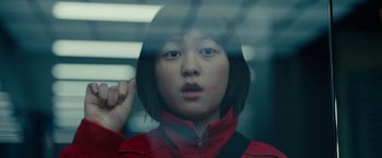 Movie still from “Okja” (2017), directed by Bong Joon Ho – A young woman in a red and black jacket looking out of a window; Close Up shot, Low angle