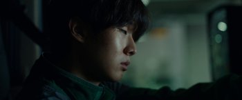 Movie still from “Okja” (2017), directed by Bong Joon Ho – A young man is looking off into the distance; Close Up shot, Low angle