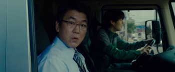 Movie still from “Okja” (2017), directed by Bong Joon Ho – A man sitting in the back seat of a car; Close Up shot, Low angle