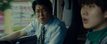 Movie still from “Okja” (2017), directed by Bong Joon Ho – A man sitting in the back seat of a car; Close Up shot, Over the shoulder angle