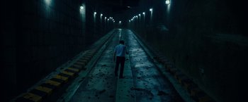 Movie still from “Okja” (2017), directed by Bong Joon Ho – A man walking down a train track in a tunnel; Extreme Wide shot, High angle