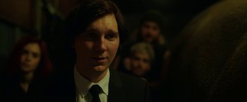 Movie still from “Okja” (2017), directed by Bong Joon Ho – A man in a suit and tie in front of other people; Close Up shot, Over the shoulder angle