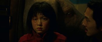 Movie still from “Okja” (2017), directed by Bong Joon Ho – A young girl and an elephant in a dark room; Close Up shot, Low angle