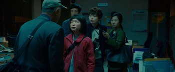 Movie still from “Okja” (2017), directed by Bong Joon Ho – A group of people standing in a room; Medium shot, Over the shoulder angle