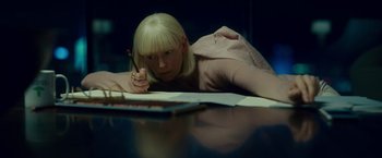 Movie still from “Okja” (2017), directed by Bong Joon Ho – A woman is laying on a table writing; Medium shot, High angle