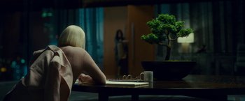 Movie still from “Okja” (2017), directed by Bong Joon Ho – A woman sitting at a table in front of a bonsai tree; Wide shot, Over the shoulder angle