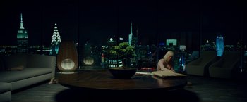 Movie still from “Okja” (2017), directed by Bong Joon Ho – A woman sitting at a table in front of a large window; Wide shot, High angle