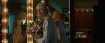 Movie still from “Okja” (2017), directed by Bong Joon Ho – A woman holding a bouquet of flowers in front of a mirror; Medium shot, Over the shoulder angle