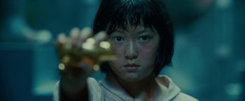 Movie still from “Okja” (2017), directed by Bong Joon Ho – A young asian girl holding a gold object; Close Up shot, High angle