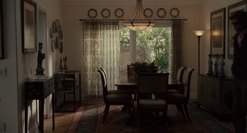 Movie still from “Moneyball” (2011), directed by Bennett Miller – A dining room table and chairs in front of a sliding glass door; Wide shot, High angle