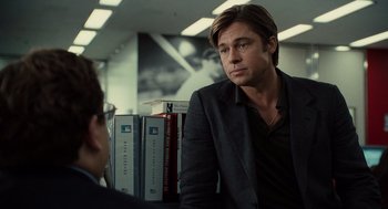 Movie still from “Moneyball” (2011), directed by Bennett Miller – A man in a black jacket is talking to another man in a black suit; Medium shot, Over the shoulder angle