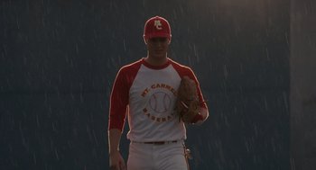 Movie still from “Moneyball” (2011), directed by Bennett Miller – A baseball player holding a catchers mitts in the rain; Medium shot, Low angle