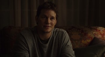 Movie still from “Moneyball” (2011), directed by Bennett Miller – A man sitting on top of a couch in front of a window; Close Up shot, Over the shoulder angle
