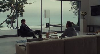 Movie still from “Moneyball” (2011), directed by Bennett Miller – Two men sitting in front of a large glass window; Wide shot, Over the shoulder angle