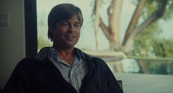 Movie still from “Moneyball” (2011), directed by Bennett Miller – A man in a blue shirt and a black jacket smiling; Medium shot, Over the shoulder angle