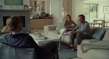 Movie still from “Moneyball” (2011), directed by Bennett Miller – A man and a woman sitting on a couch in a living room; Wide shot, Over the shoulder angle