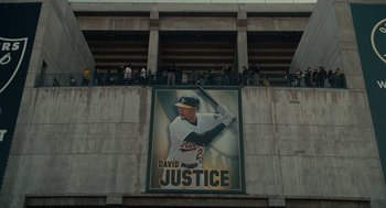 Movie still from “Moneyball” (2011), directed by Bennett Miller – A large poster of a baseball player on the side of a building; Extreme Wide shot, Overhead angle