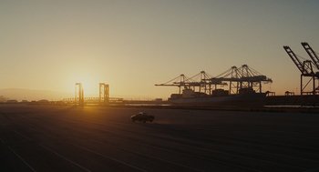 Movie still from “Moneyball” (2011), directed by Bennett Miller – A car is driving on a road near a bridge; Extreme Wide shot, Low angle