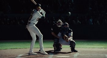 Movie still from “Moneyball” (2011), directed by Bennett Miller – A baseball player swinging a bat at a game; Wide shot, Low angle
