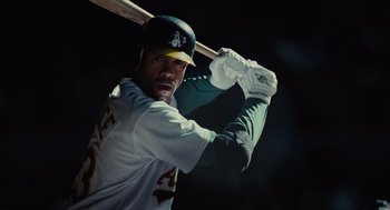 Movie still from “Moneyball” (2011), directed by Bennett Miller – A man holding a baseball bat while standing in the dark; Medium shot, Low angle