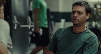 Movie still from “Moneyball” (2011), directed by Bennett Miller – A man in a green shirt is in a gym; Close Up shot, Over the shoulder angle