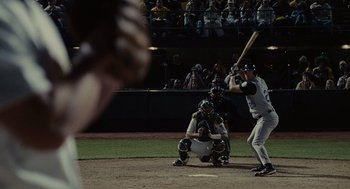 Movie still from “Moneyball” (2011), directed by Bennett Miller – A baseball player holding a bat on top of a baseball field; Medium shot, Over the shoulder angle