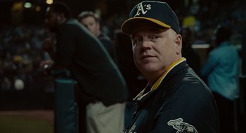 Movie still from “Moneyball” (2011), directed by Bennett Miller – A man in a baseball uniform is looking at the camera; Close Up shot, Over the shoulder angle