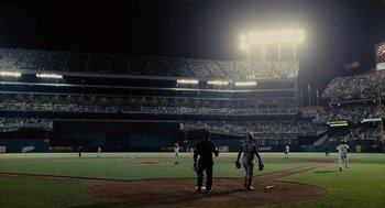 Movie still from “Moneyball” (2011), directed by Bennett Miller – Two baseball players standing on a baseball field at night; Extreme Wide shot, Over the shoulder angle
