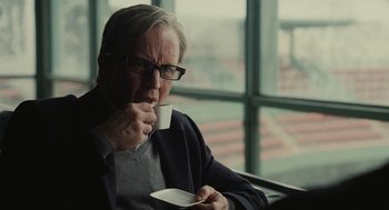 Movie still from “Moneyball” (2011), directed by Bennett Miller – A man with glasses is drinking a cup of coffee; Close Up shot, Over the shoulder angle