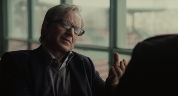 Movie still from “Moneyball” (2011), directed by Bennett Miller – An older man wearing glasses is sitting in front of a window; Close Up shot, Over the shoulder angle