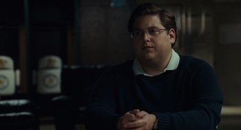 Movie still from “Moneyball” (2011), directed by Bennett Miller – A man sitting in front of a microphone in a room; Close Up shot, Over the shoulder angle