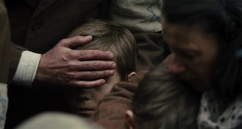 Movie still from “Operation Finale” (2018), directed by Chris Weitz – A man holding his hand over the head of a child; Close Up shot, Over the shoulder angle