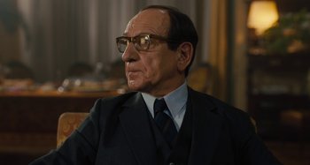 Movie still from “Operation Finale” (2018), directed by Chris Weitz – An older man wearing a suit and tie; Close Up shot, Over the shoulder angle